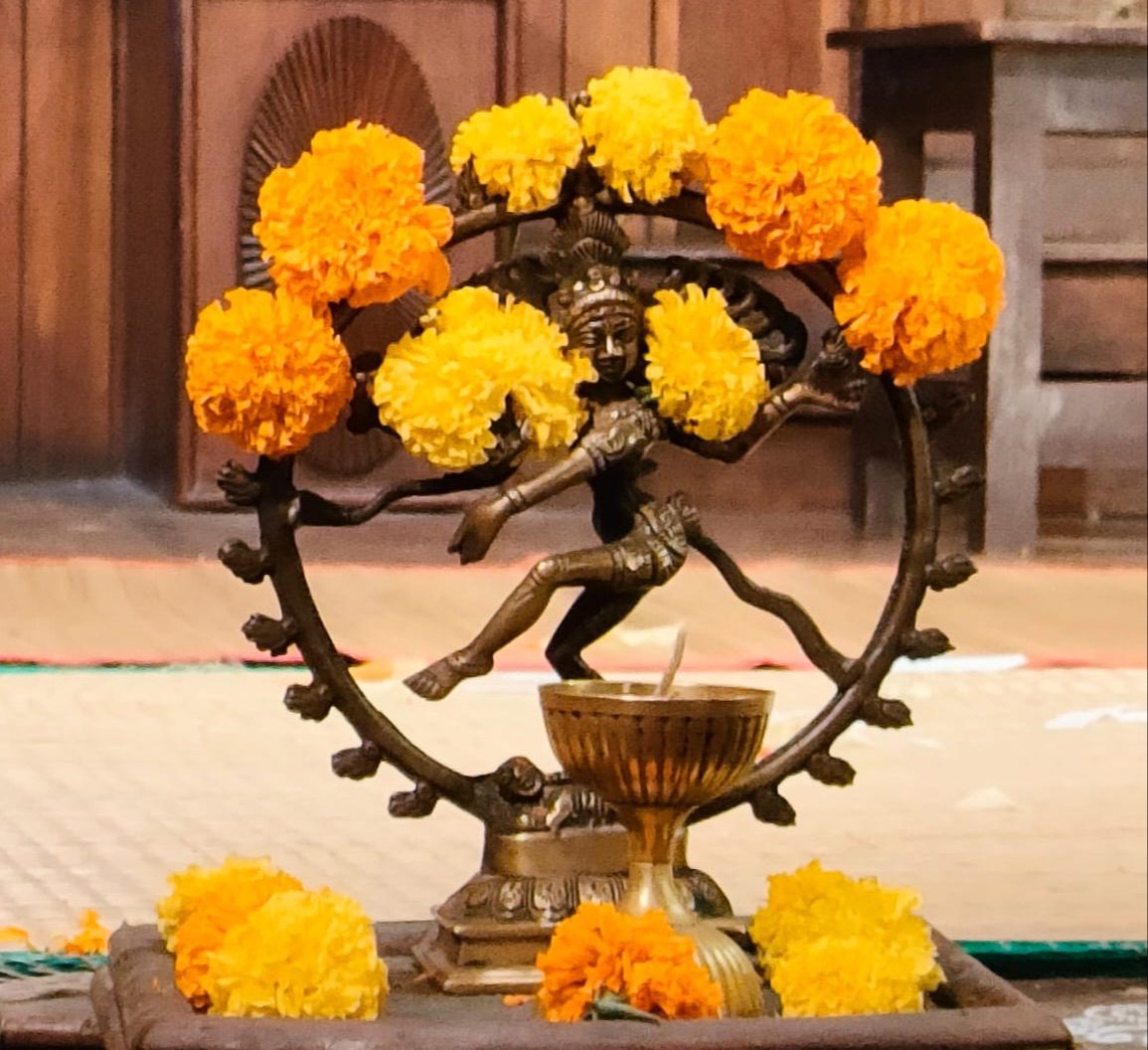 Estatua de bronce de Nataraja rodeada de flores de cempasúchil