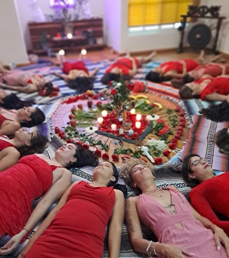Participantes descansando en círculo alrededor de un mandala de rosas y velas